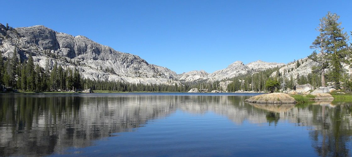 The lake in the foreground with the hills and pine trees in the background.